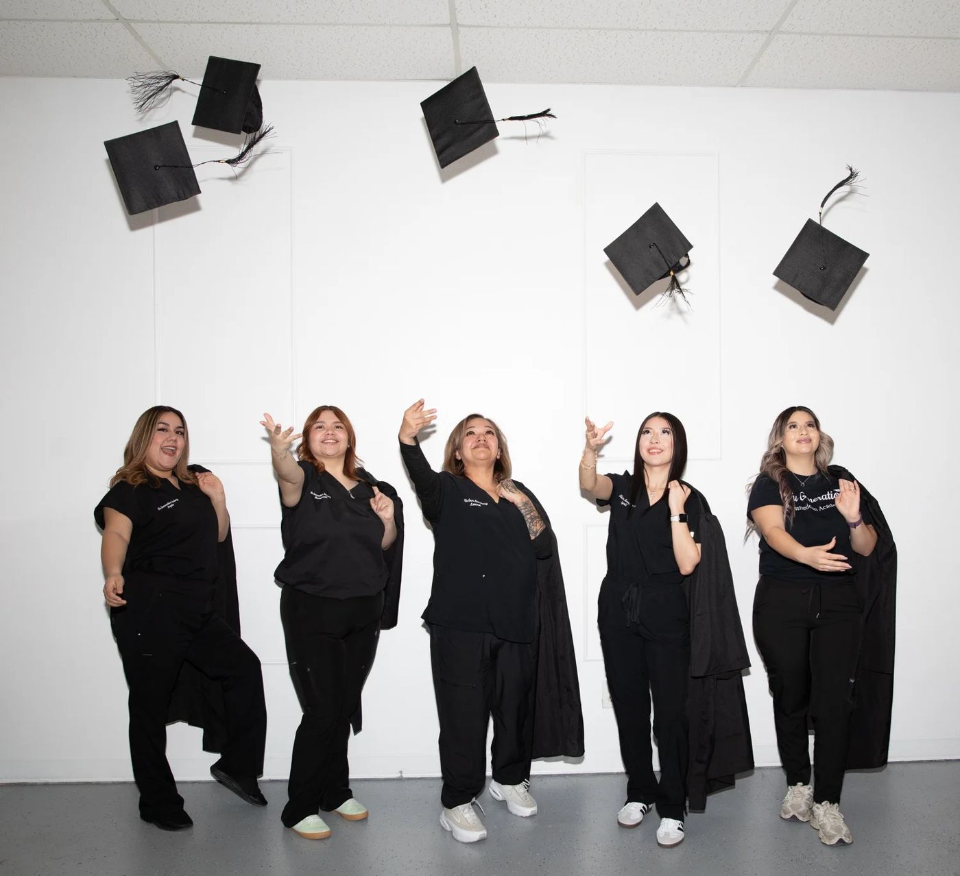 Beauty academy class tossing graduation caps